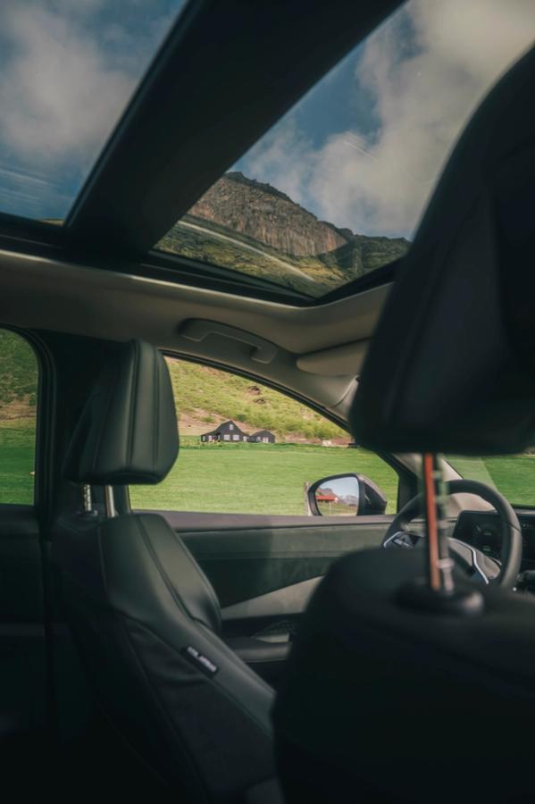 Innrétting Nissan Ariya með víðáttumiklu glerþaki og útsýni yfir fjöll og sveitabyggingar