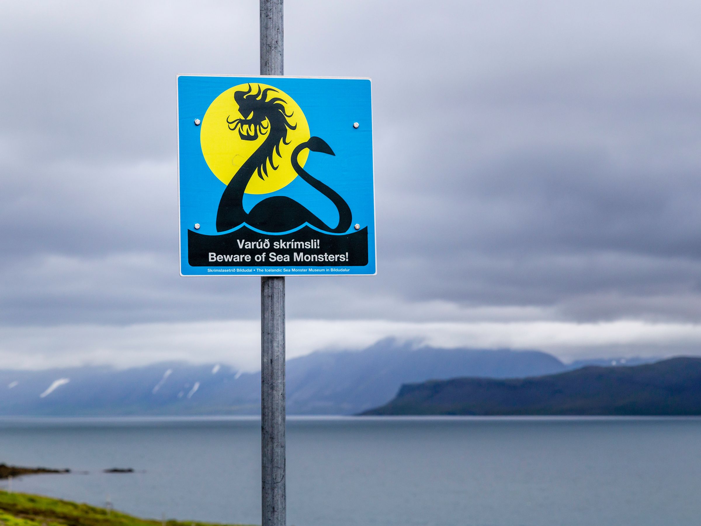 a sign on a pole warning people to beware of sea monsters .