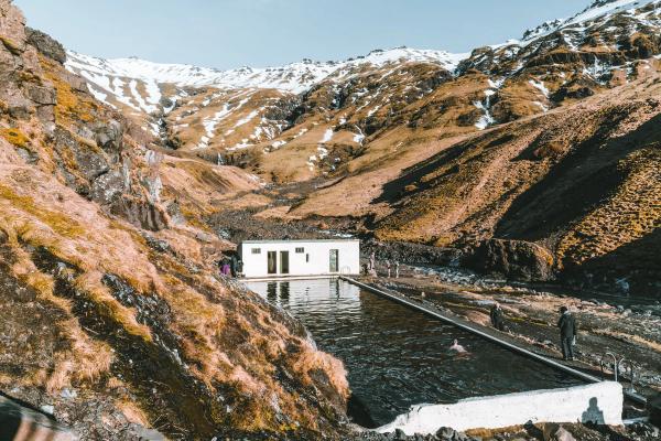 a man is standing next to a pool in the middle of a mountain in iceland.