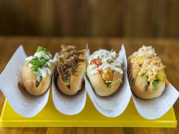 una bandeja amarilla con cuatro perritos calientes