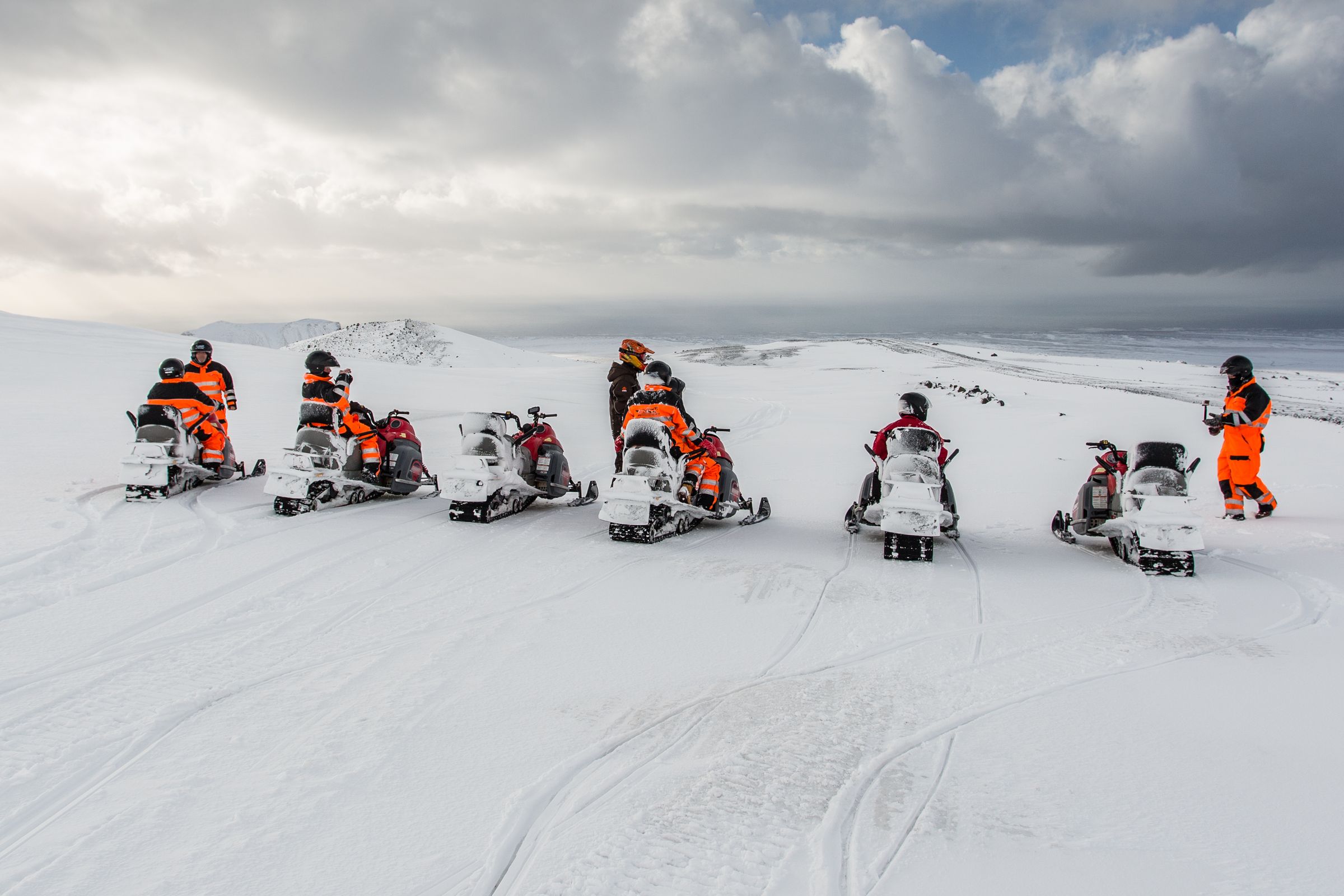 a group of people are riding snowmobiles in the snow .