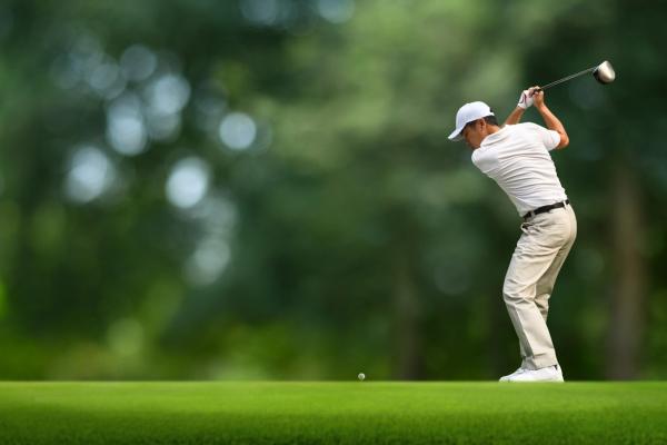 un hombre vestido de blanco golpeando una pelota de golf