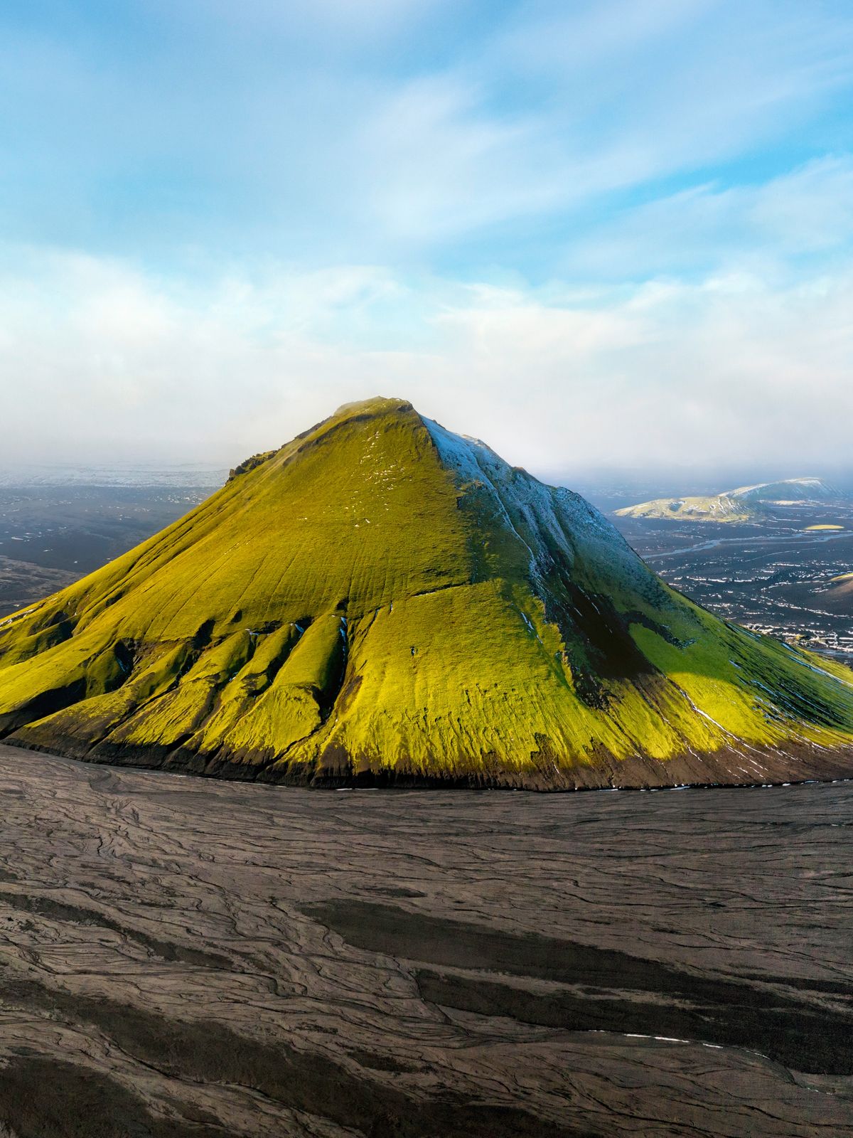 una vista aérea de una montaña verde con un cielo azul de fondo.