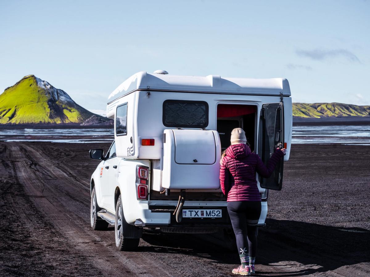 Camper Rear Door Open Woman opening the rear door of a 4x4 camper on a gravel track, campervan rental Iceland
