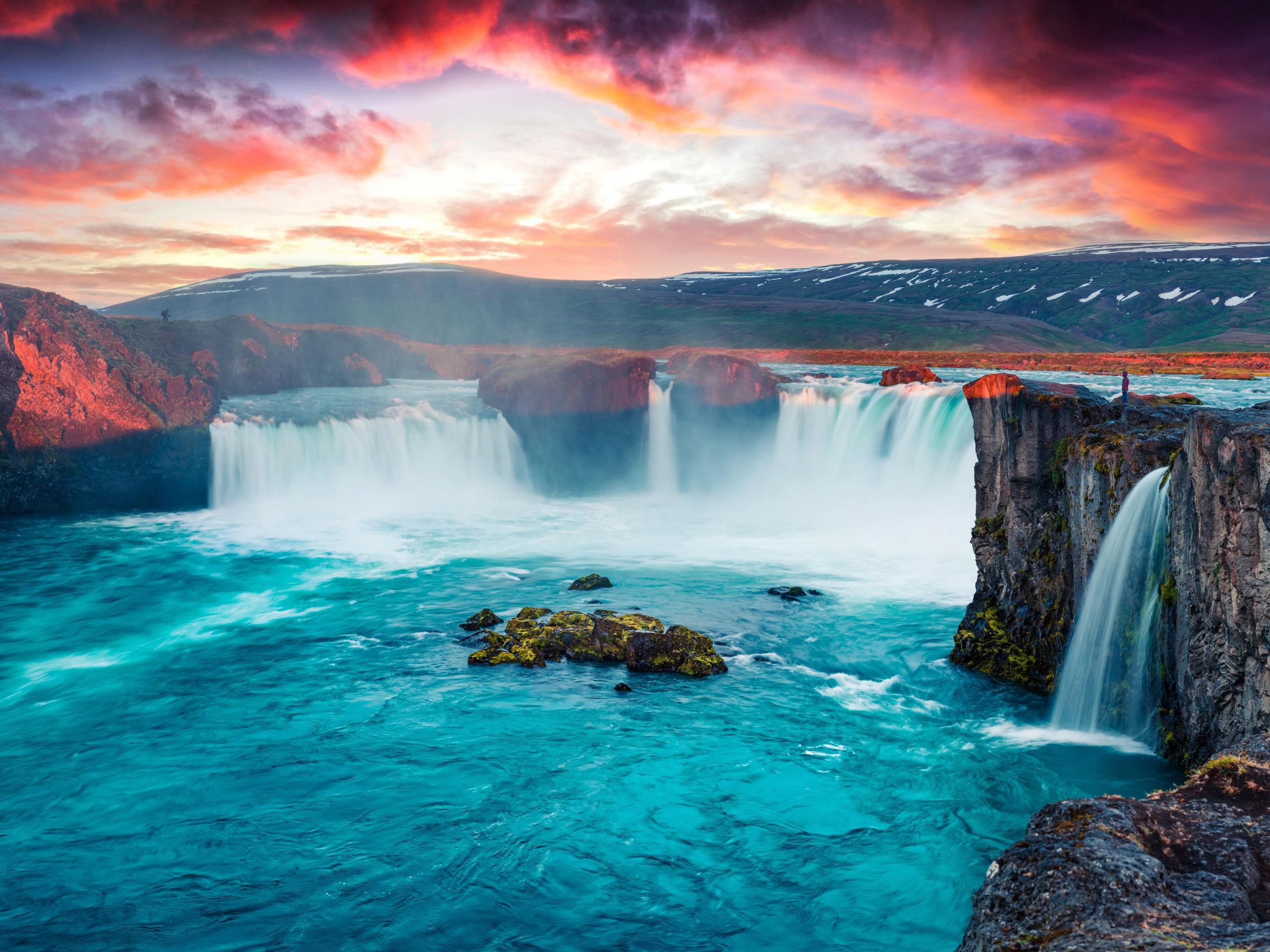 a waterfall in the middle of a river at sunset .