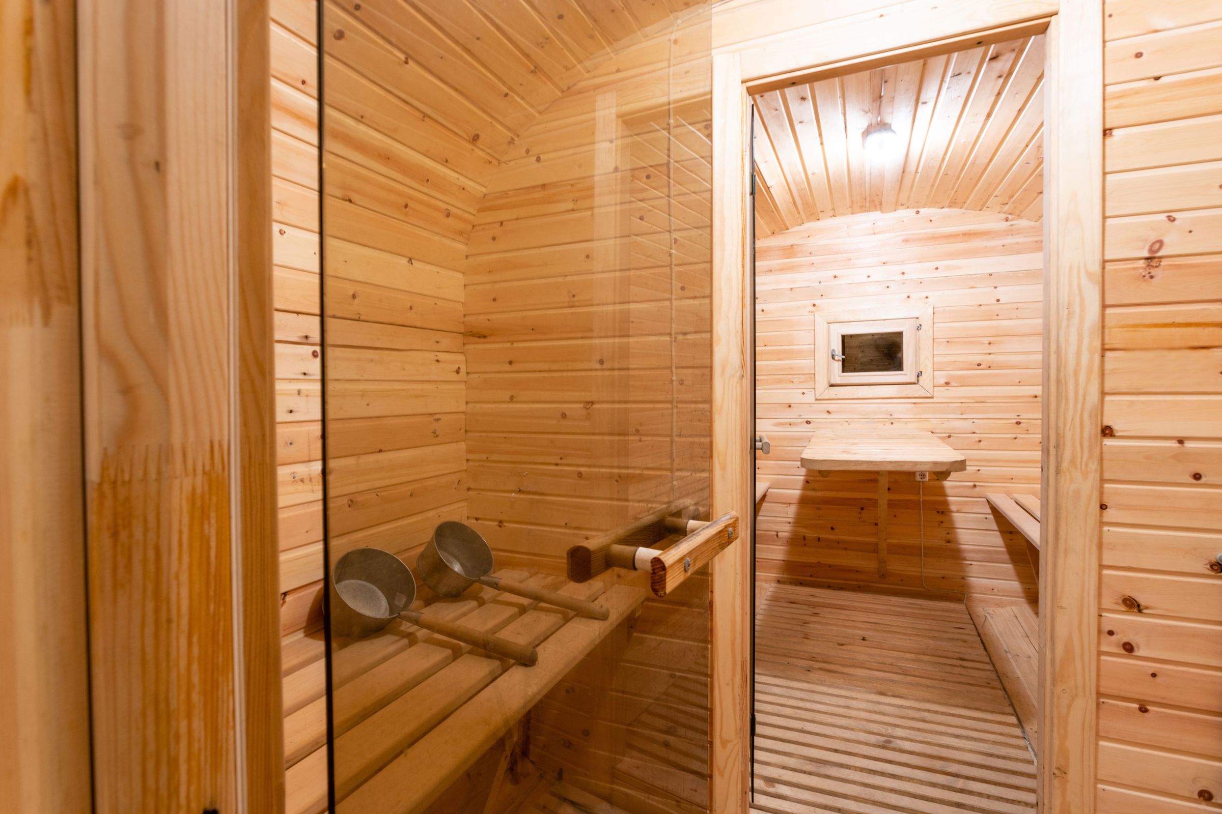 a wooden sauna with a glass door and benches .