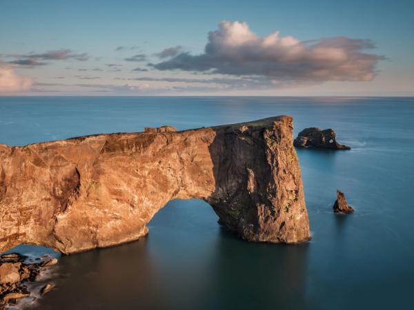 Dyrhólaey cliff in iceland with sun setting in the background