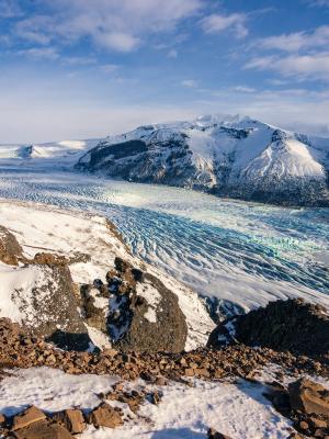 a person is standing on top of a snow covered mountain looking at a glacier .
