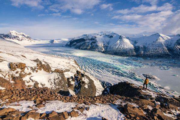 a hiker admiring a glacier tongue on a sunny day