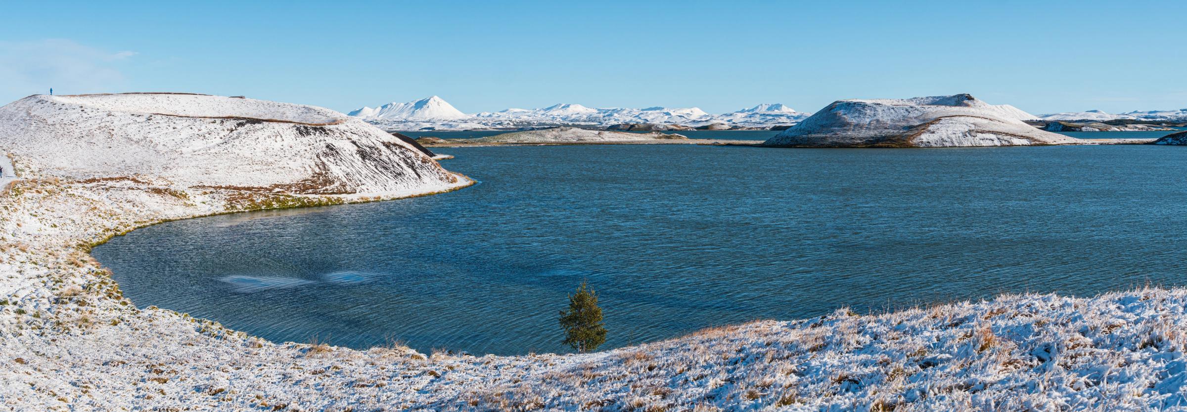 cráteres cubiertos de nueve al lado de un tranquilo lago