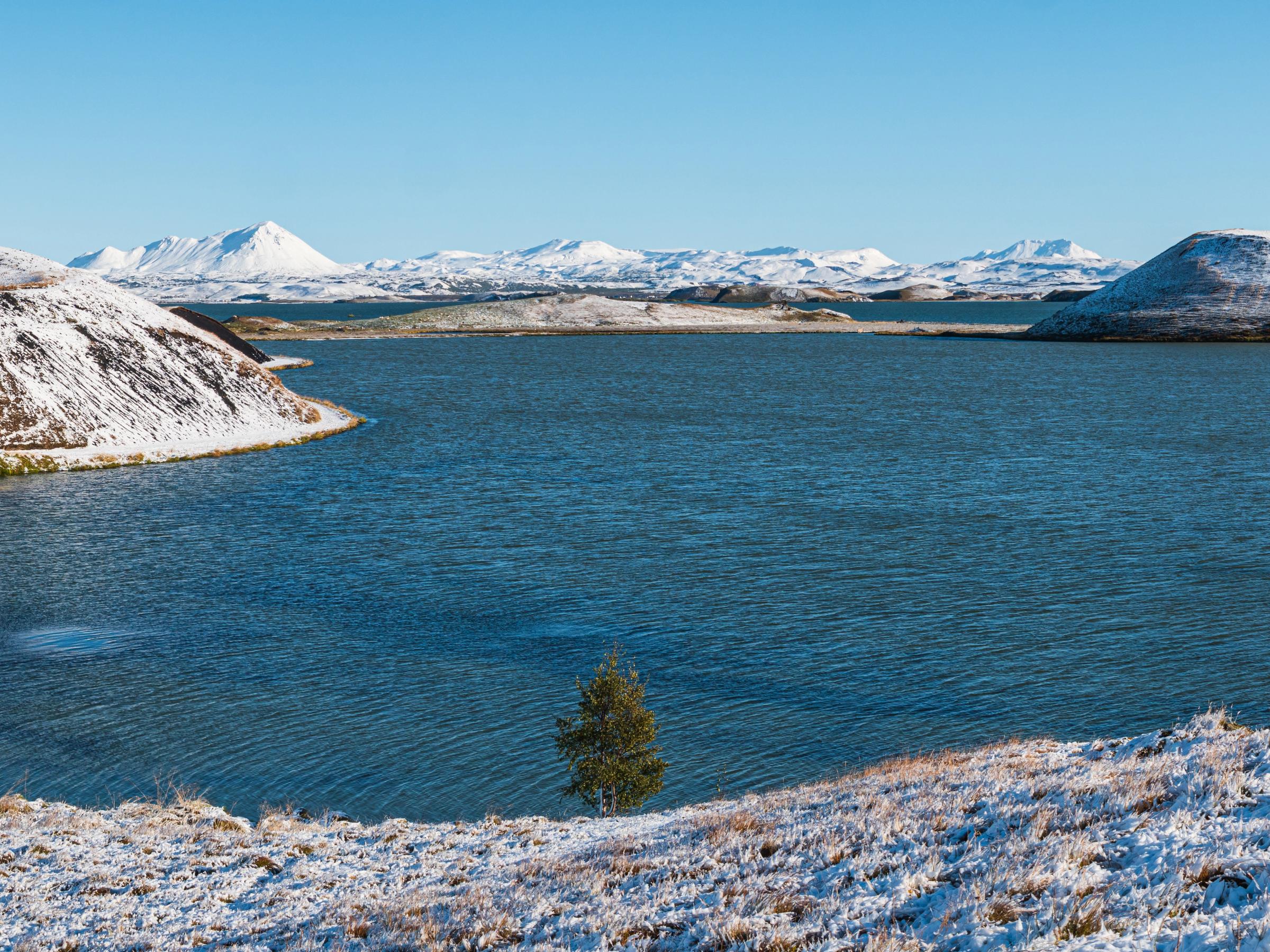 cráteres cubiertos de nueve al lado de un tranquilo lago