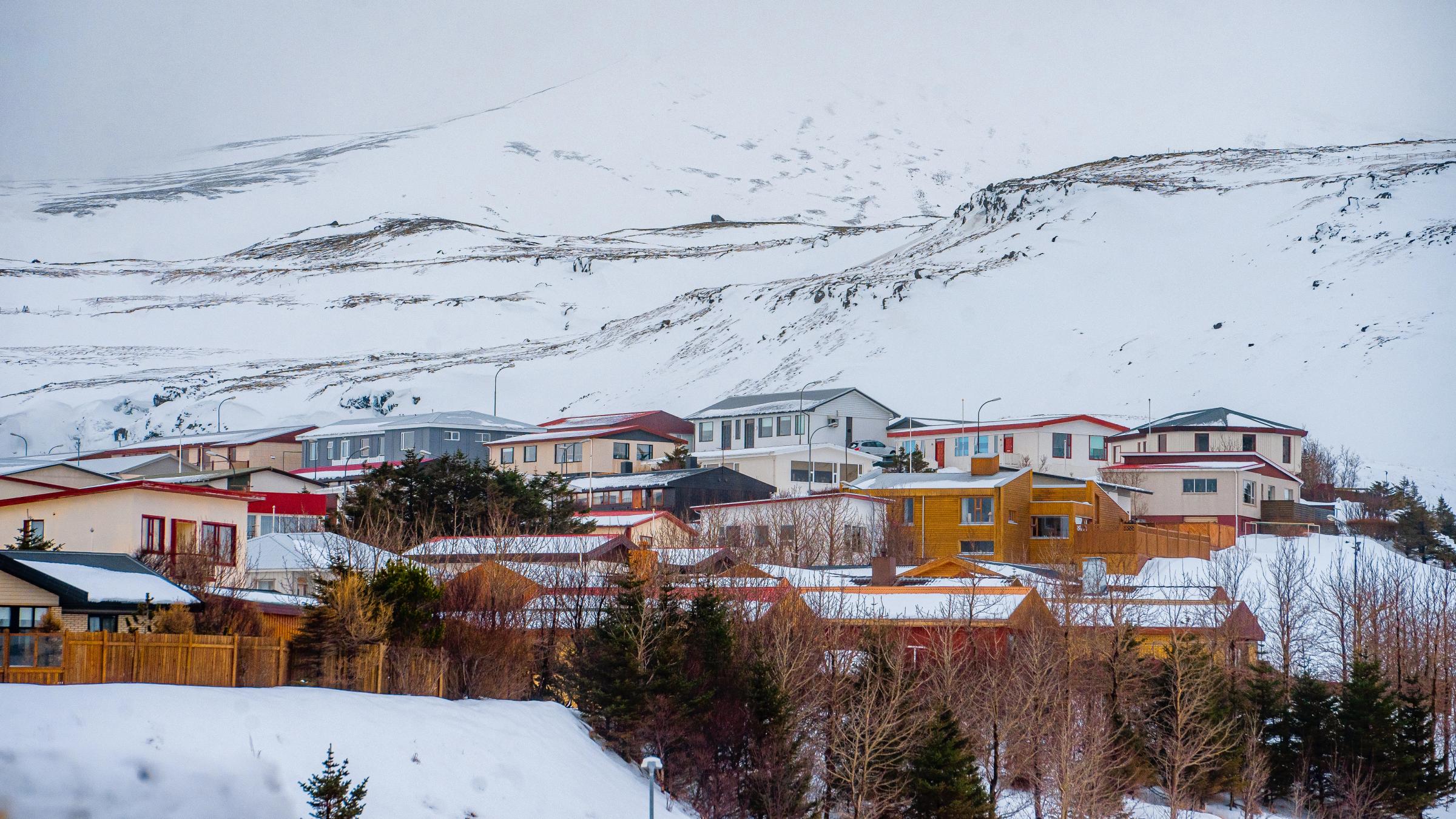 Colorful houses in a snow-covered village with a large mountain backdrop.