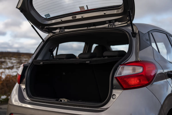 Rear view of a grey Hyundai i10 hatchback with its empty trunk open.
