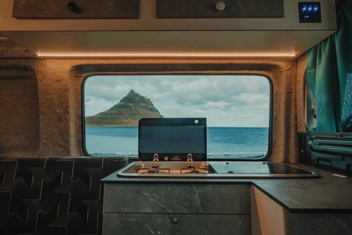 Encimera de cocina con placa de dos fuegos, armarios altos y una ventana con vistas al mar