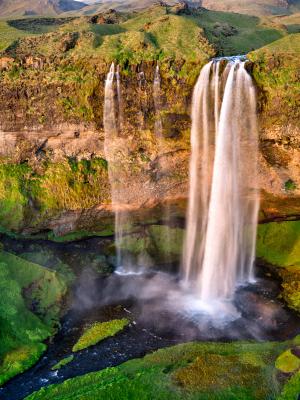 an aerial view of a waterfall in the middle of a green field .