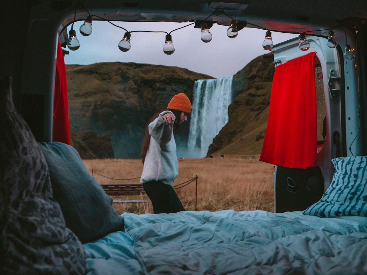 a woman is standing in front of a waterfall in the back of a van
