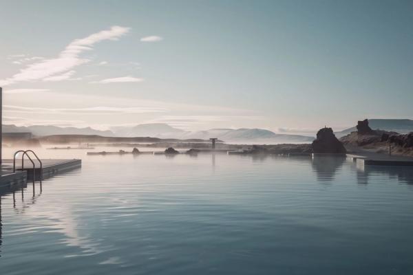 a large swimming pool with mountains in the background and a building in the background .