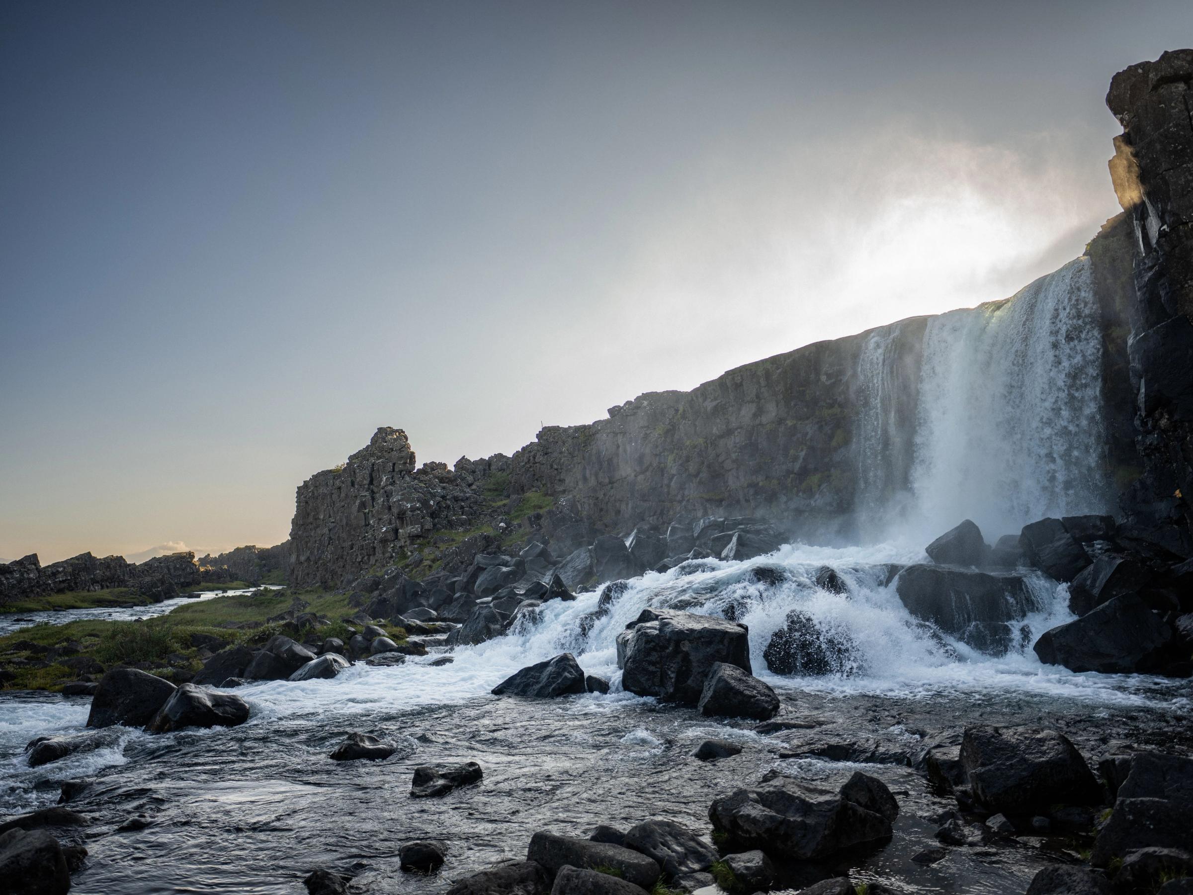 a waterfall is surrounded by rocks and a river .