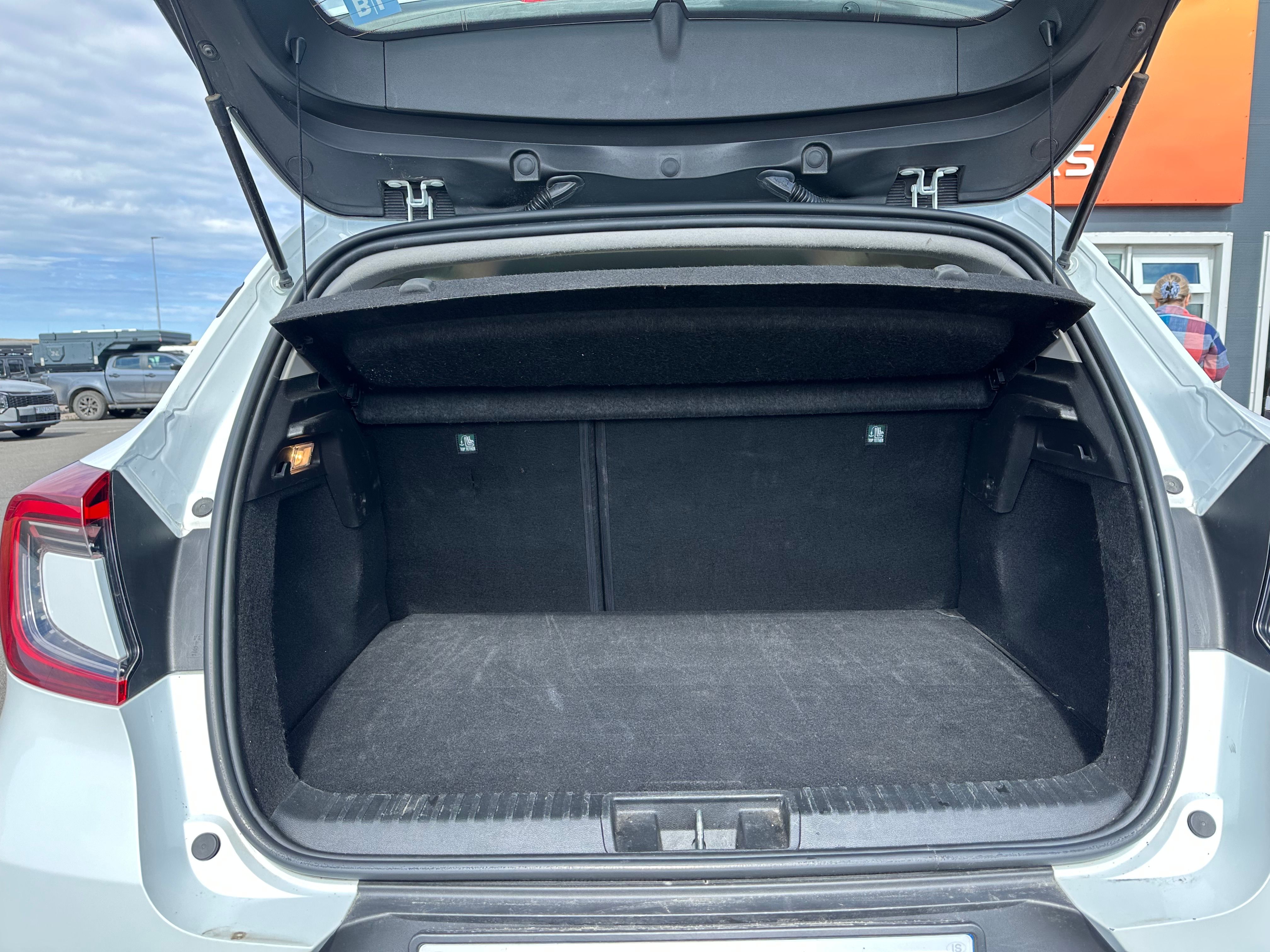 Open and empty trunk of a light-colored car with a cargo cover.