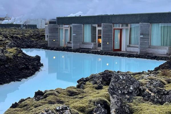 a house with a large pool in front of it surrounded by rocks .