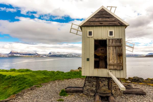 a small windmill is sitting on top of a rocky hill overlooking a body of water .