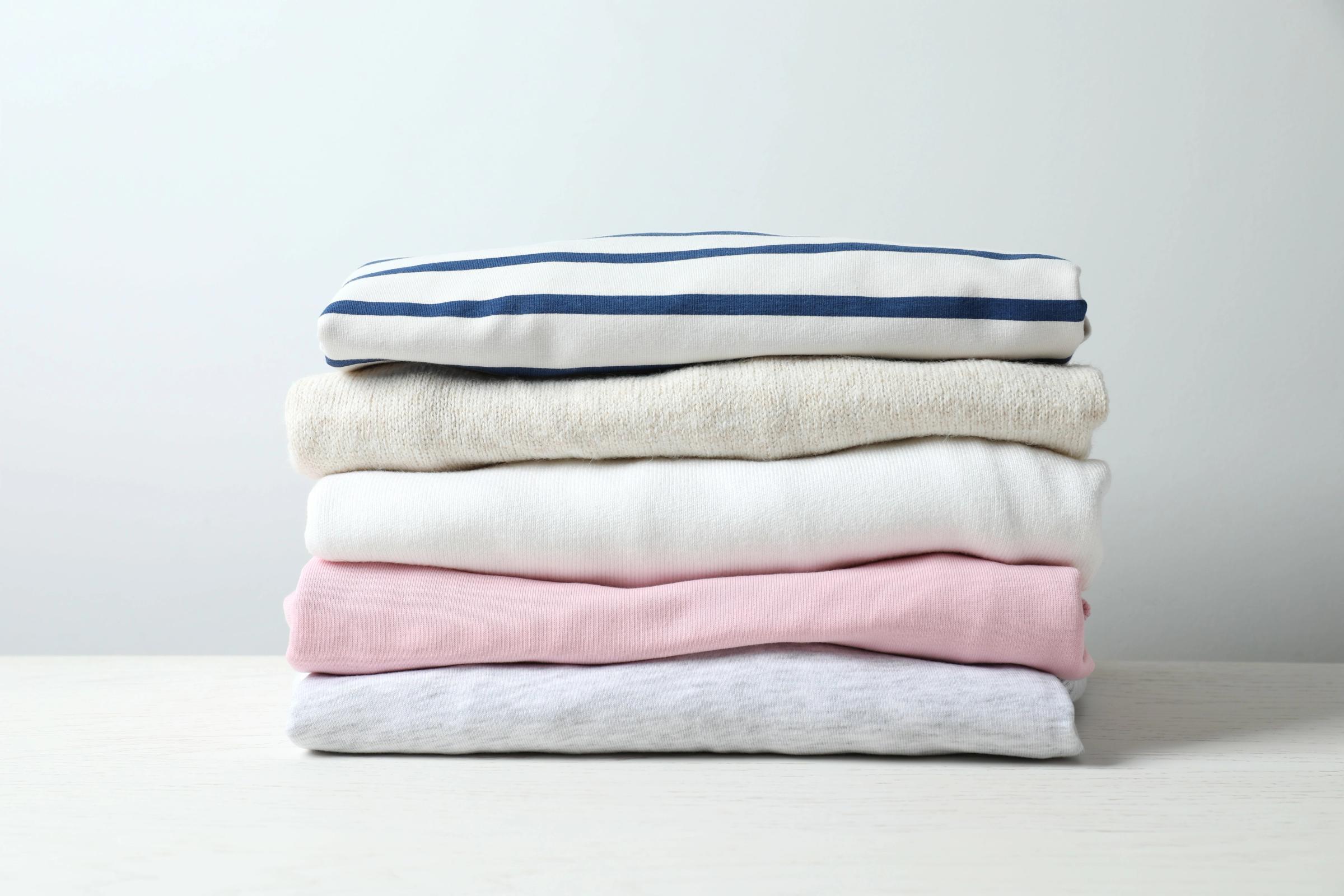 una pila de ropa doblada sobre una mesa blanca.