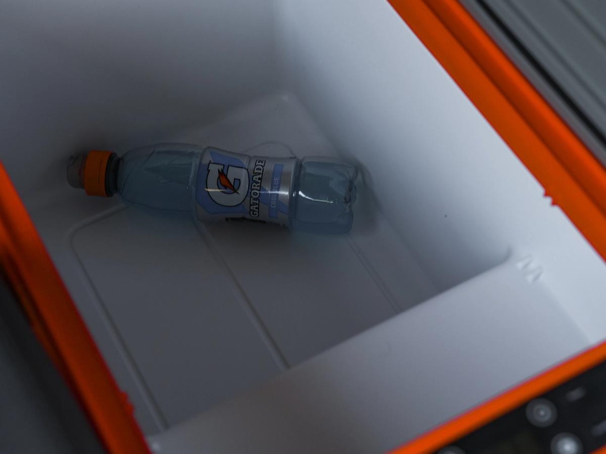 Lok kæliboxsins er opið Kælibox með opnu loki, stafrænum stjórnhnöppum og vatnsflösku inni í