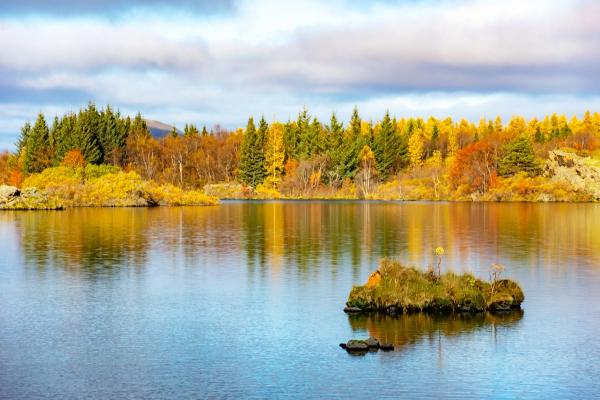 Lake with a small island and vibrant autumn trees reflecting in the water.