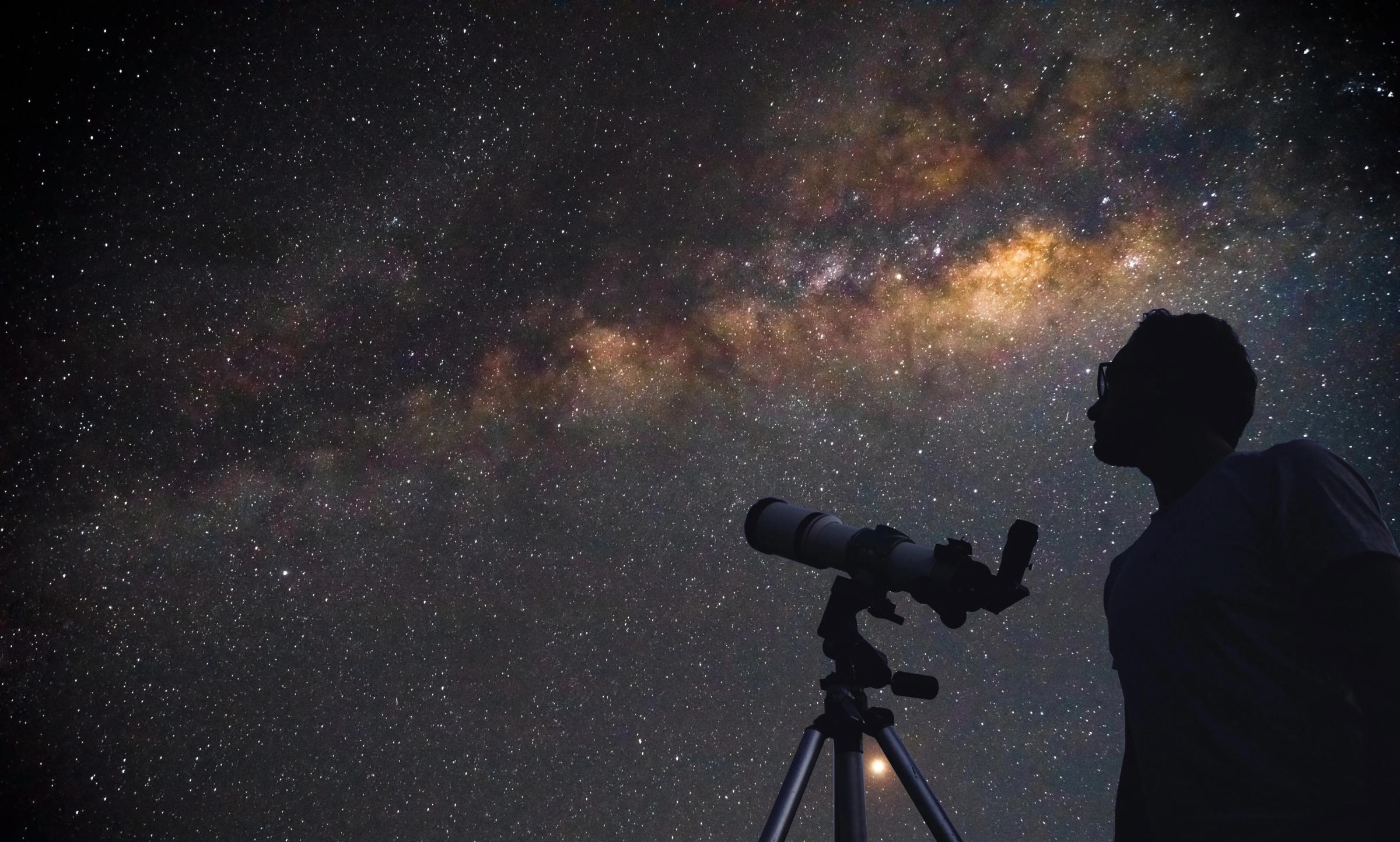 un hombre con un telescopio observando el cielo estrellado