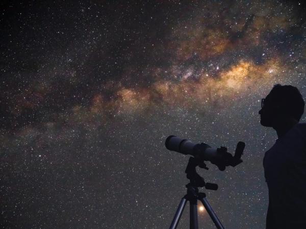 un hombre con un telescopio observando el cielo estrellado