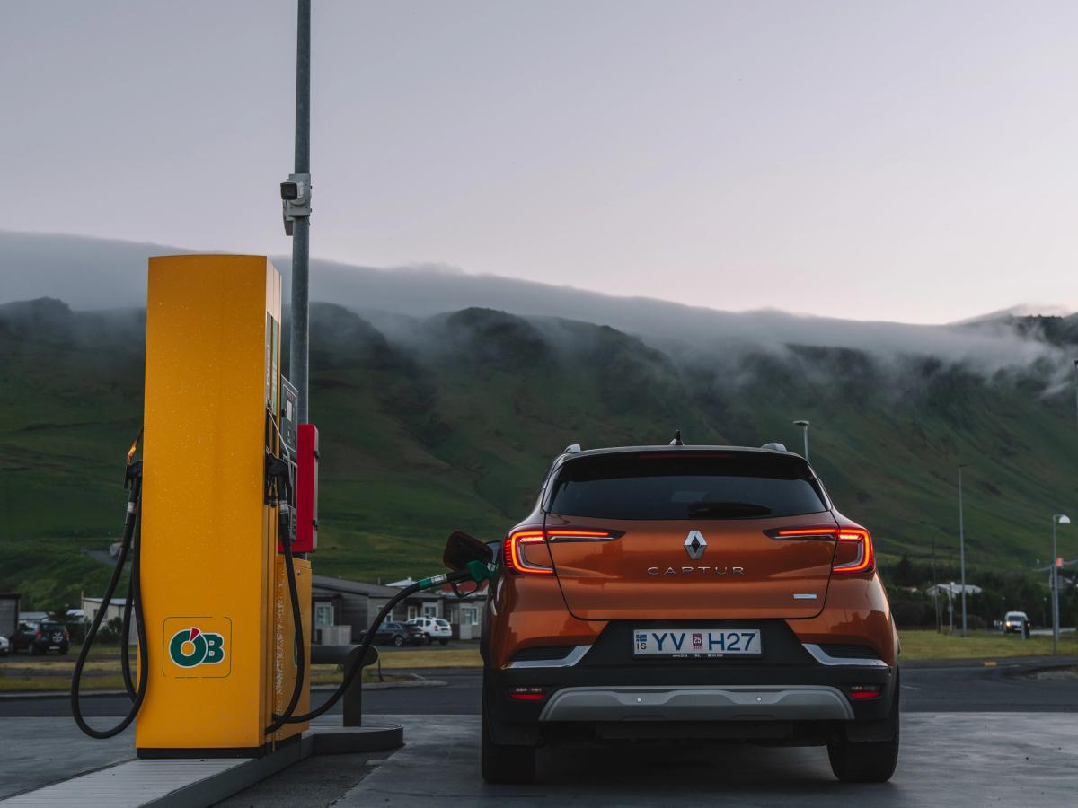 Gasolinera para Renault Captur Vista trasera de un Renault Captur aparcado junto a un surtidor de combustible, con colinas cubiertas de niebla al fondo