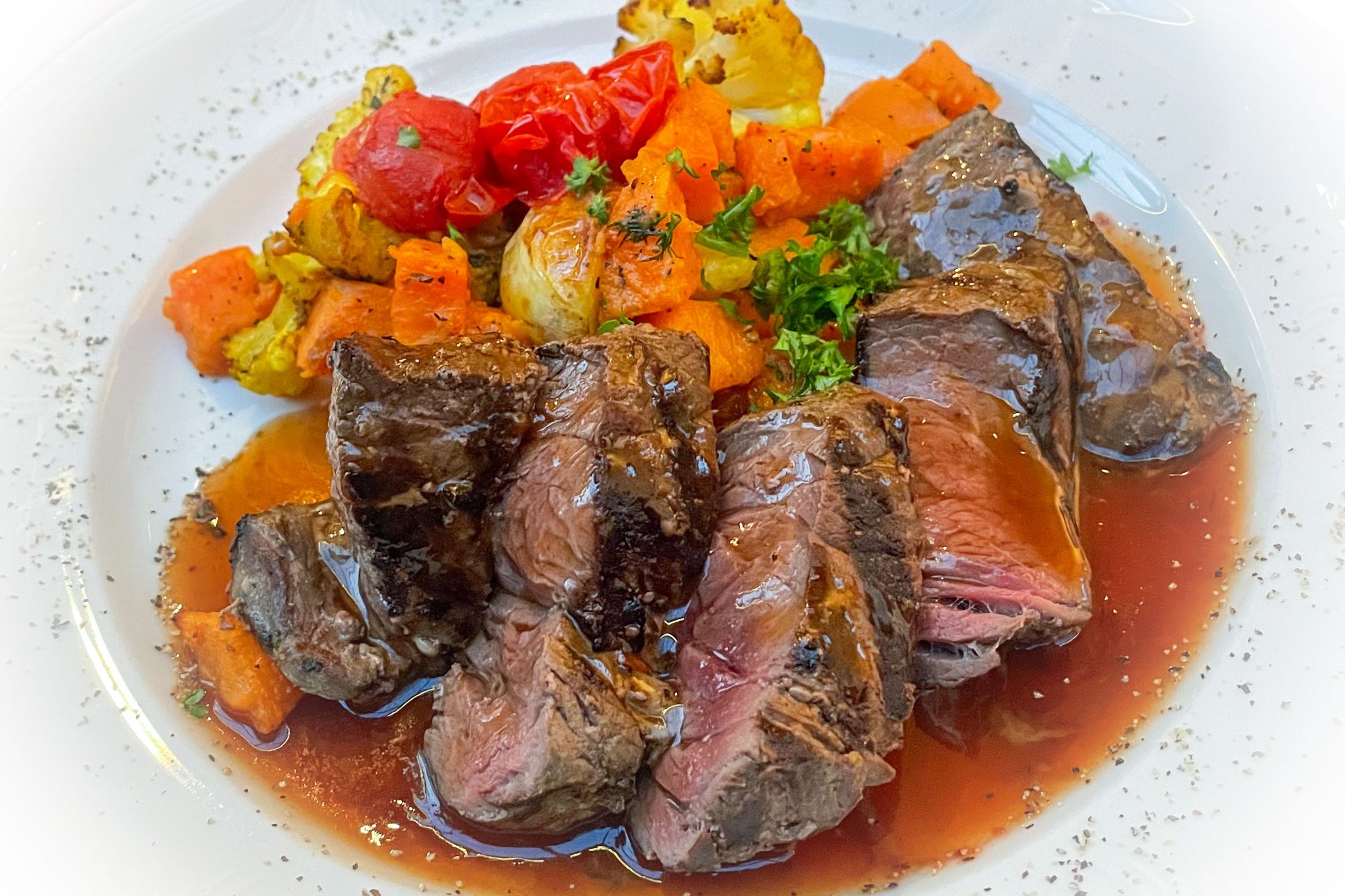 a white plate topped with steak and vegetables on a table .