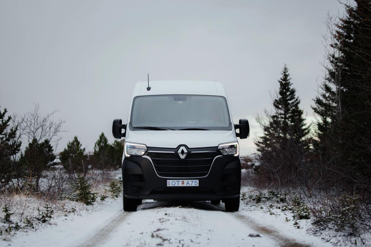Ein großer Camper für 5 Personen, von vorne zwischen Nadelbäumen zu sehen, Camper mieten in Island