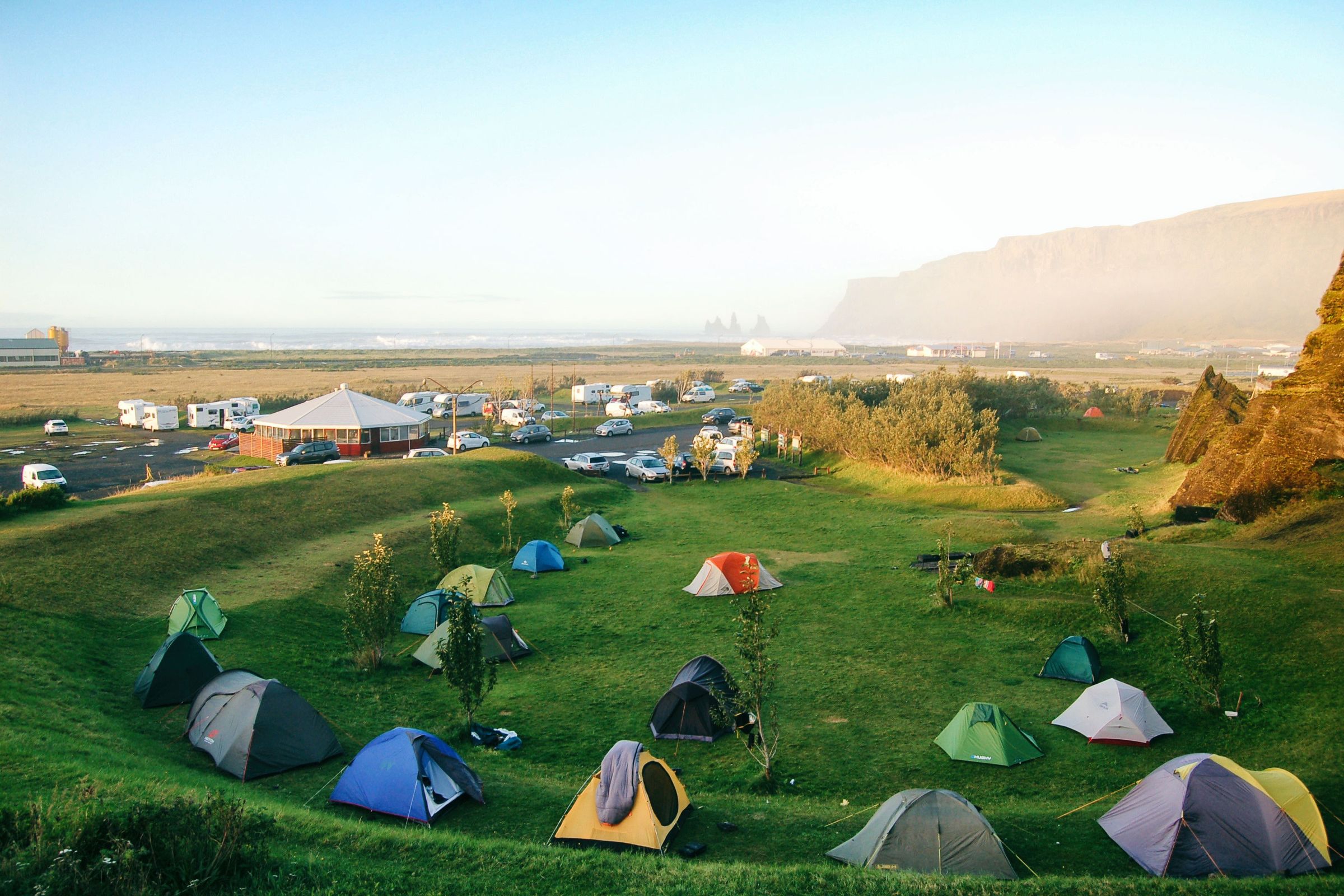 des tentes colorées sur un champ d'herbe avec une plage en arrière-plan