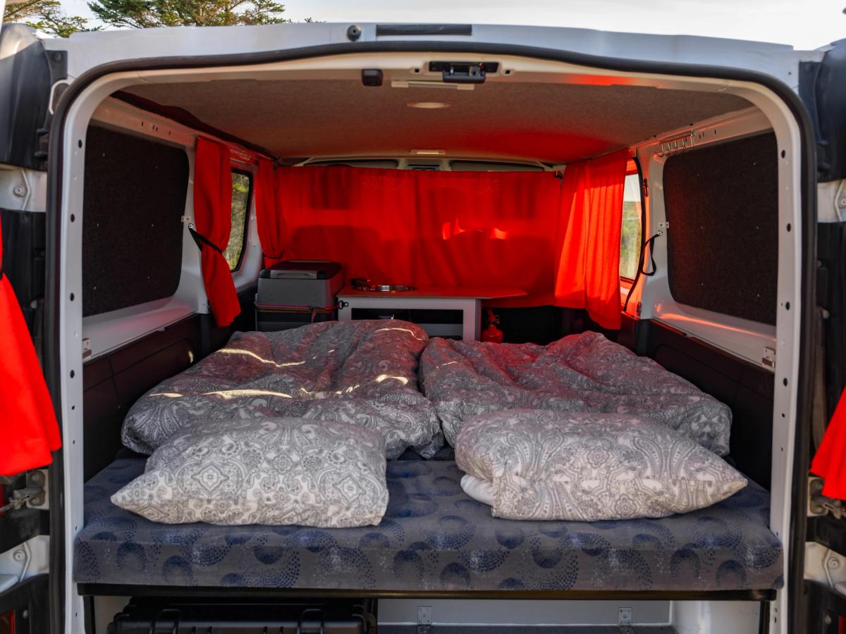 Configuración con dos edredones individuales Cama preparada con 2 edredones colocados uno al lado del otro, vista a través de las puertas traseras abiertas