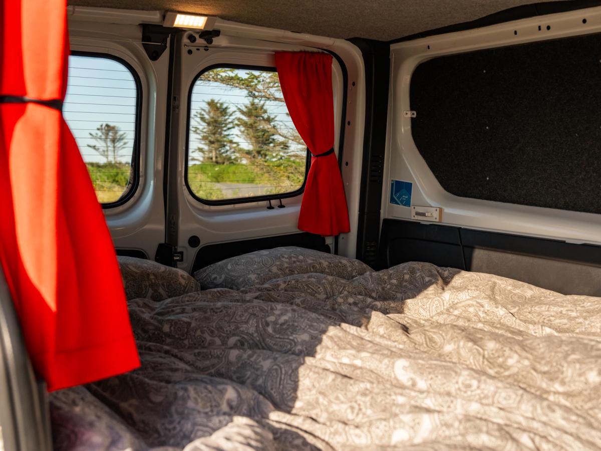 Ventanillas traseras descubiertas Ventanillas de las puertas traseras con las cortinas recogidas sobre la cama y la luz del techo encendida