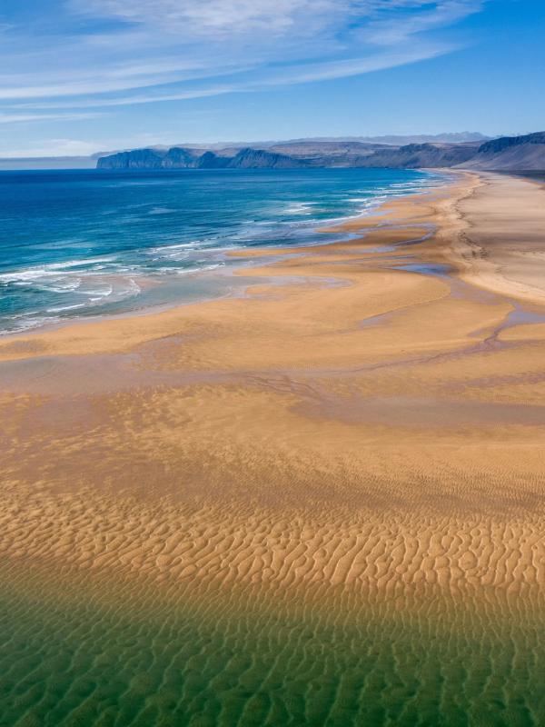an aerial view of a long sandy beach next to the ocean .