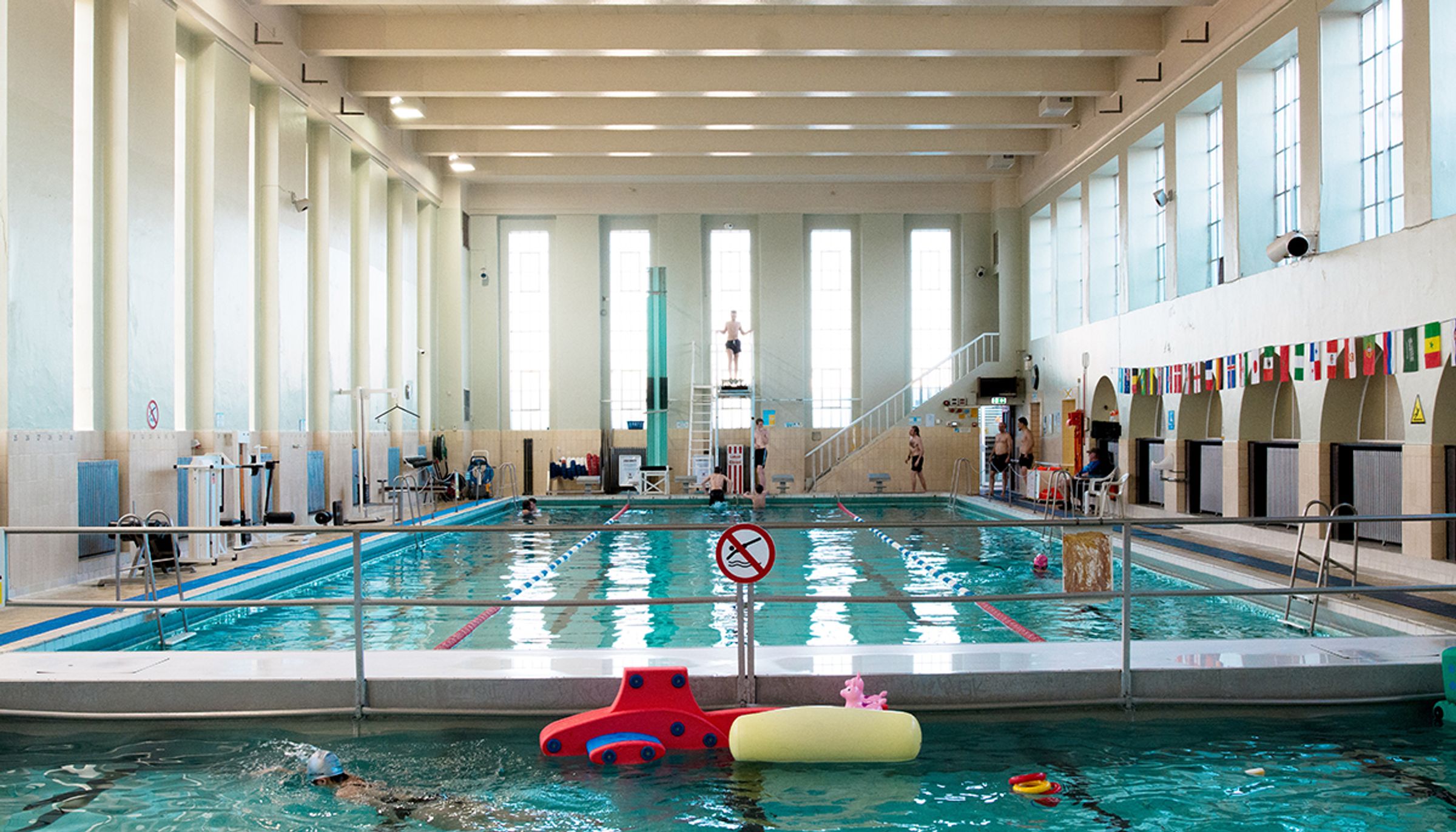 a large indoor swimming pool with people swimming in it .