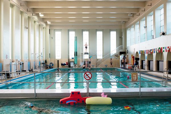 a large indoor swimming pool with people swimming in it .