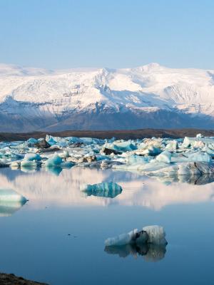 a lake filled with icebergs and mountains in the background .