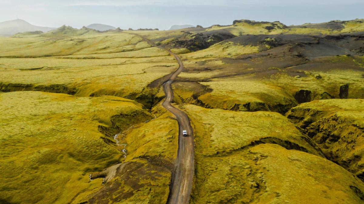 una vista aérea de un coche conduciendo por un camino de tierra.
