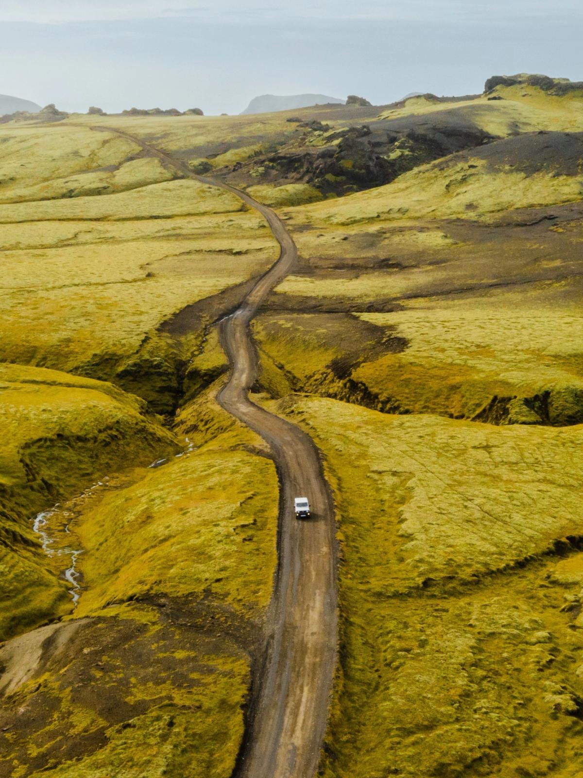 una vista aérea de un coche conduciendo por un camino de tierra.
