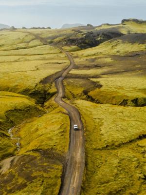 an aerial view of a car driving down a dirt road .