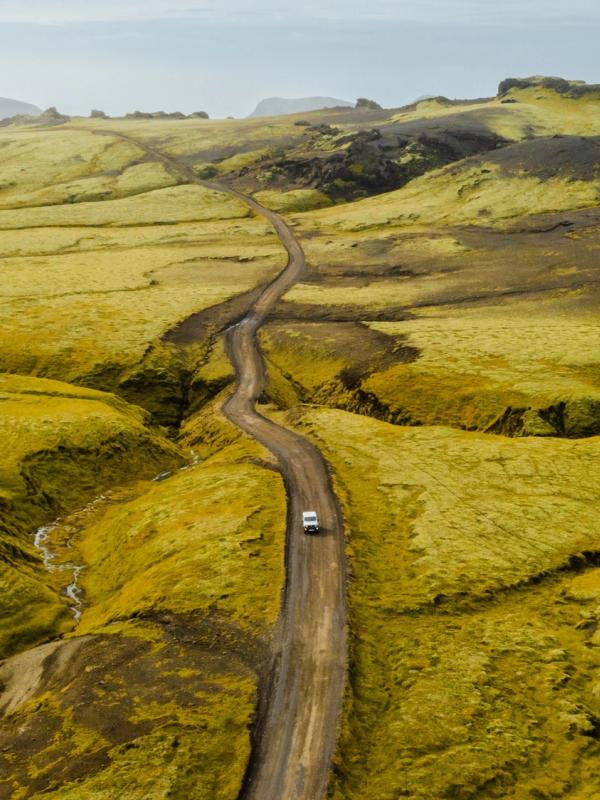 una vista aérea de un coche conduciendo por un camino de tierra.