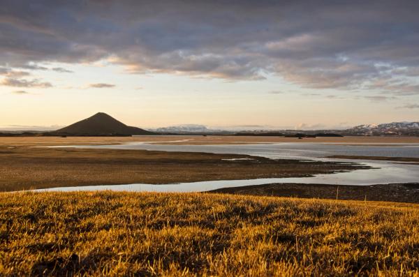 a lake with a mountain in the background and a grassy hill in the foreground .