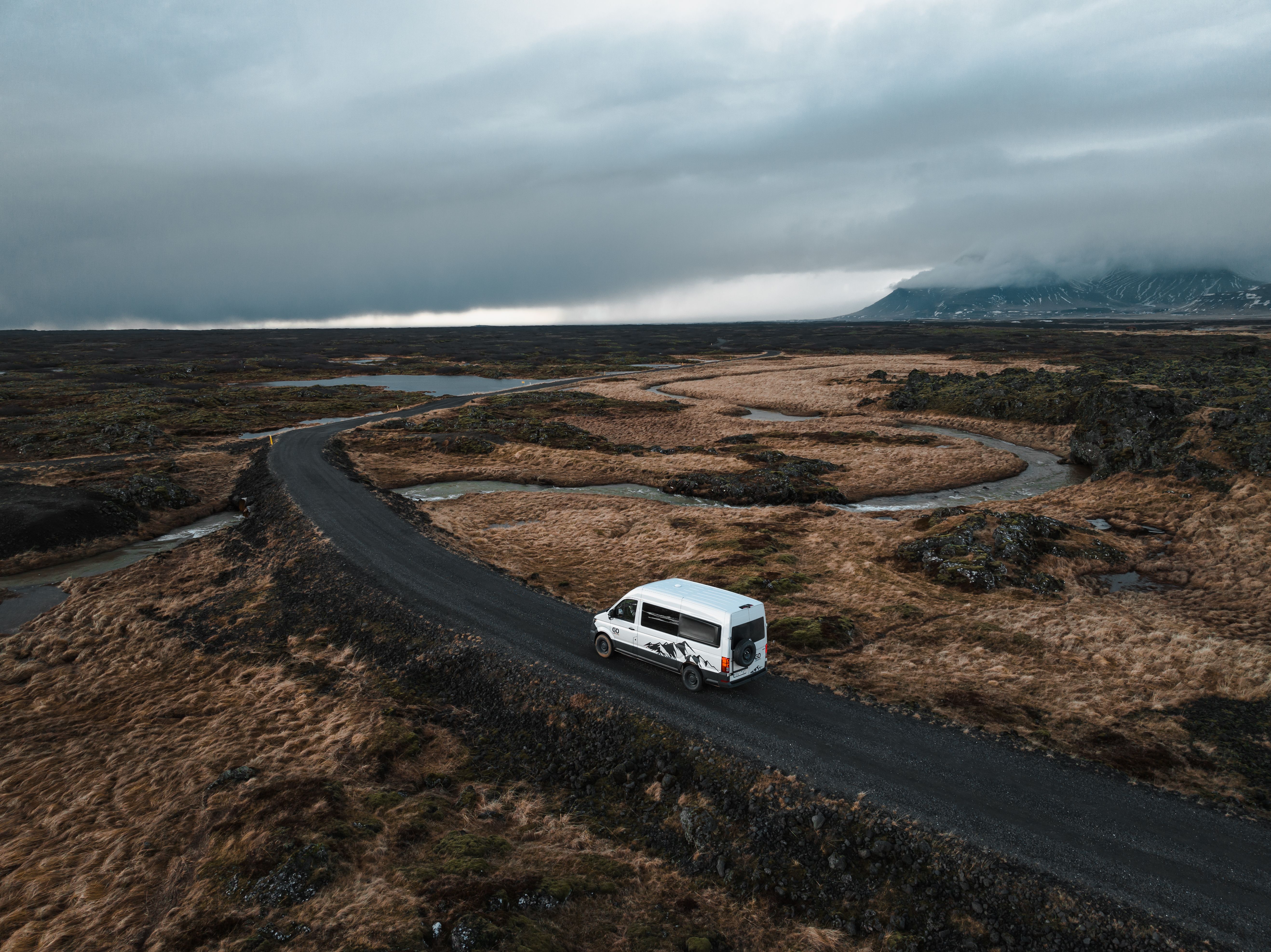 Vista aérea de la autocaravana en una carretera sinuosa junto a pequeños arroyos, alquiler de autocaravanas 4x4 en Islandia