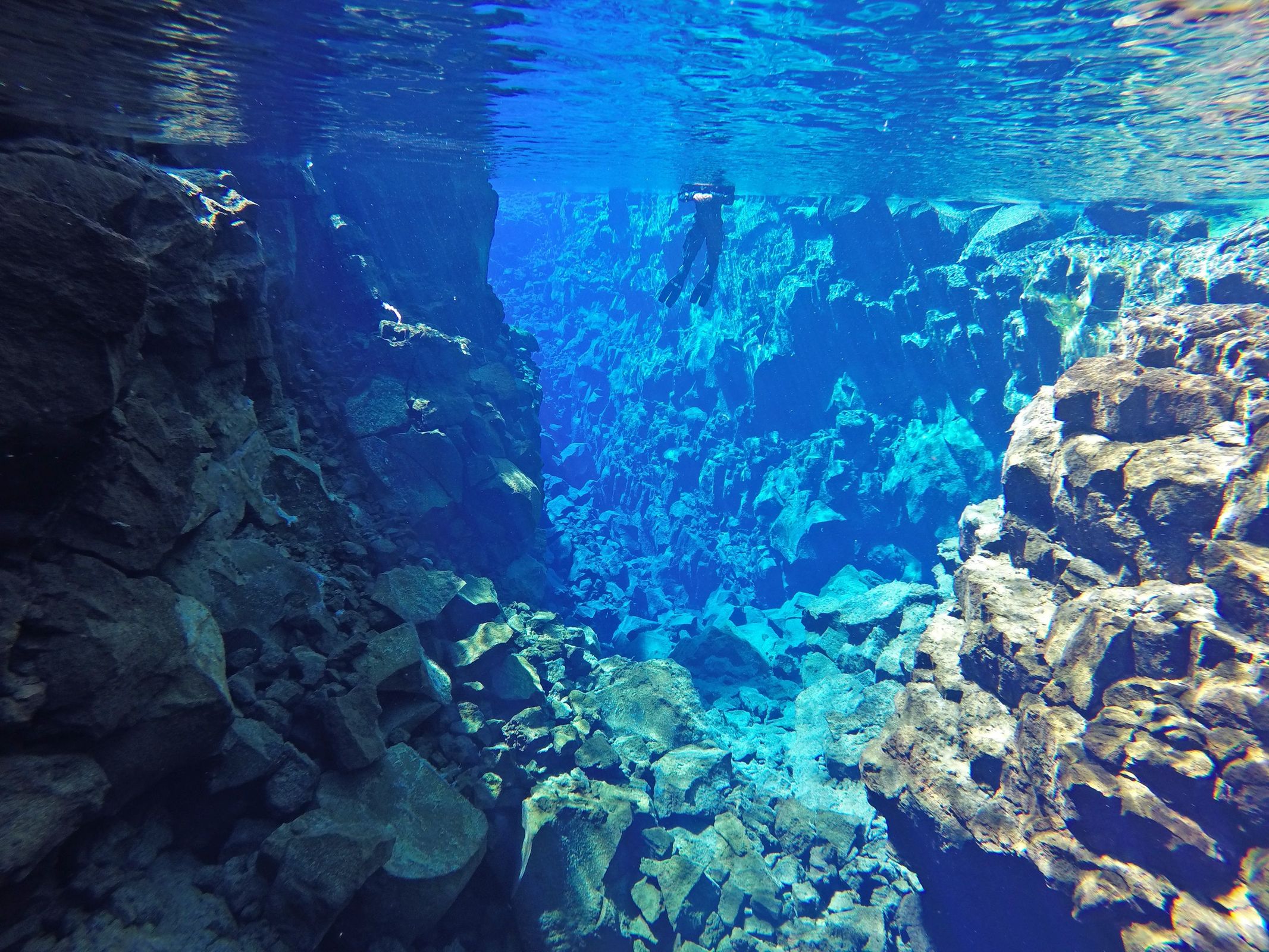 a person is swimming in a cave in the ocean .