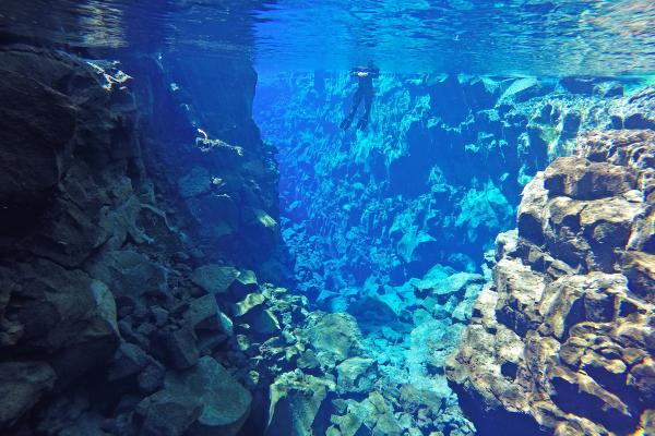 a person is swimming in a cave in the ocean .