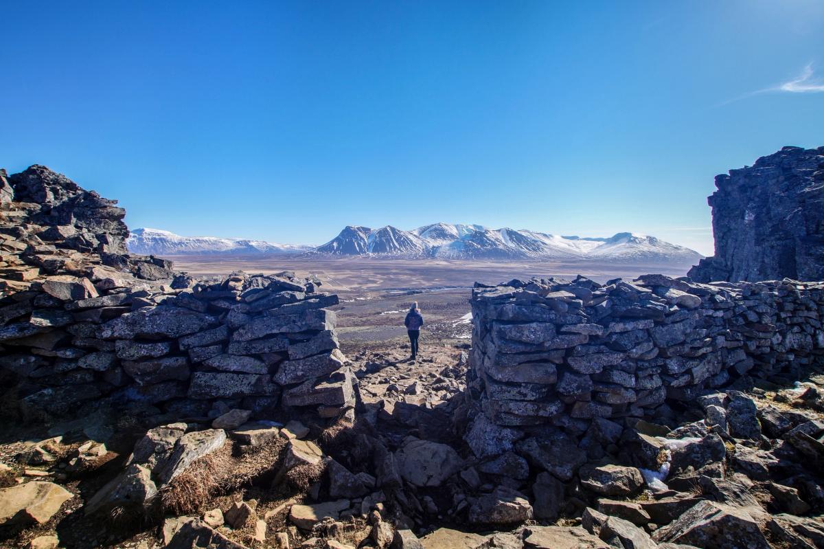 un hombre está de pie en la cima de una montaña rocosa mirando las montañas .