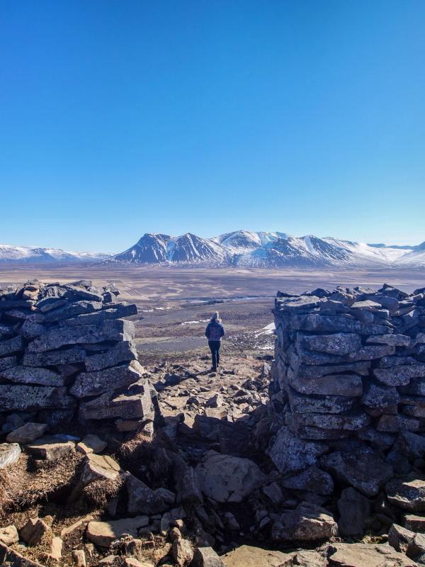 a man is standing on top of a rocky mountain looking at the mountains .